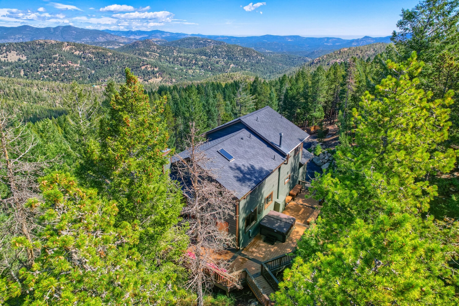 Aerial view of the rear of the property showing the deck and surrounding forest