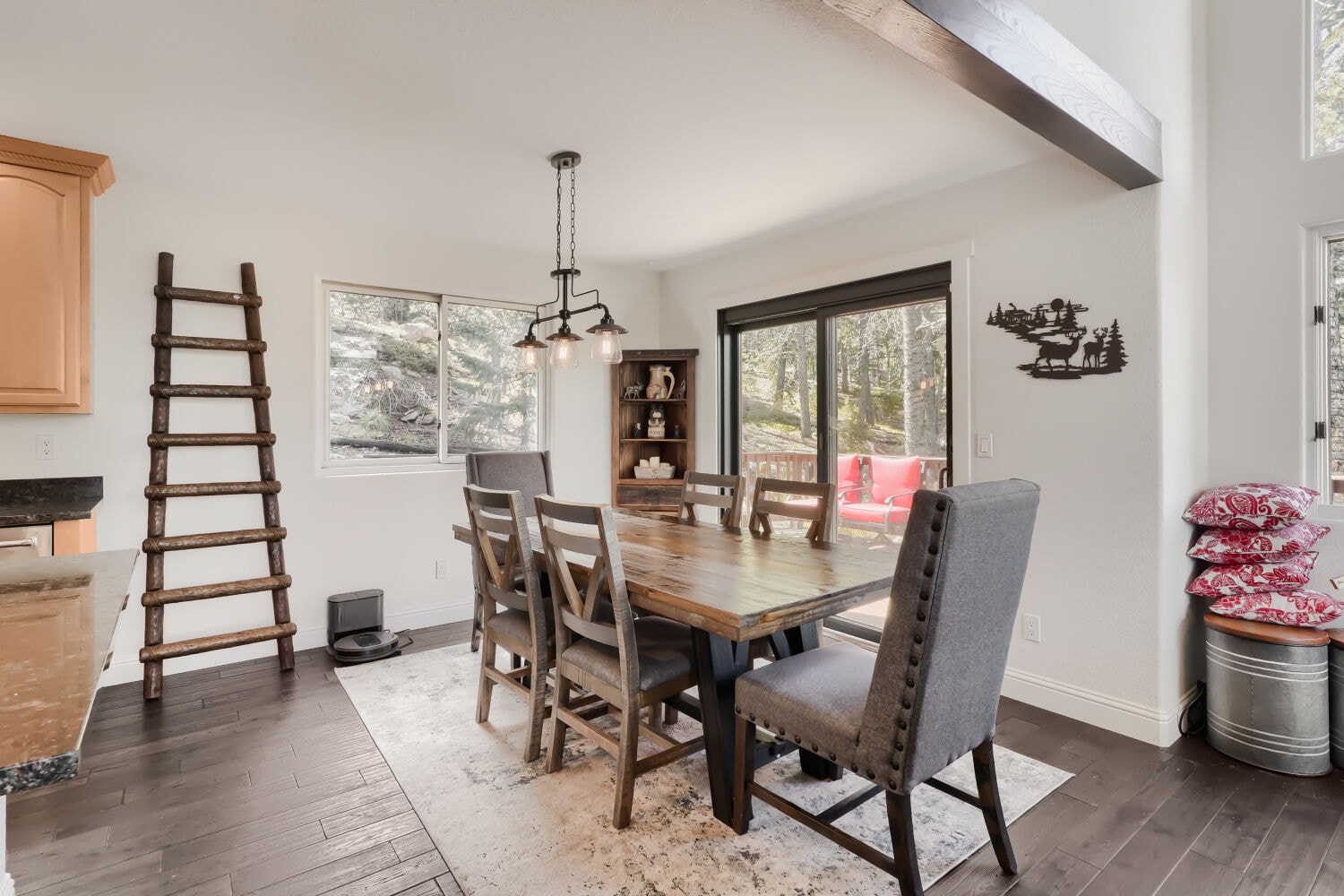Dining room with exposed beam ceiling, rustic wood table, and forest views