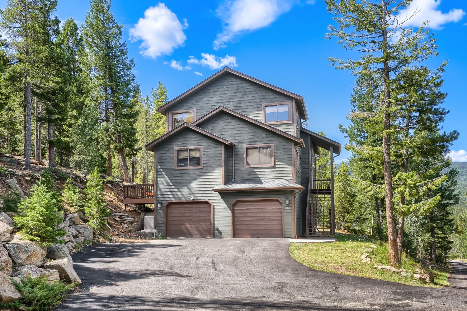 Front exterior of 8352 Martin Lane — green siding, two-car garage, mountain setting